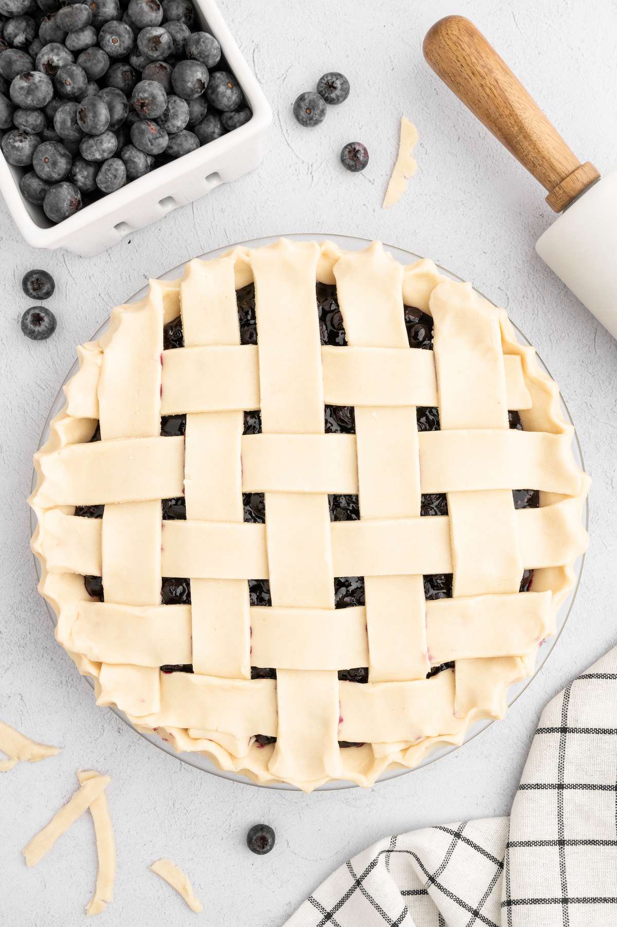 Vegan pie crusts with a blueberry filling in a pie dish, with a lattice design on top.