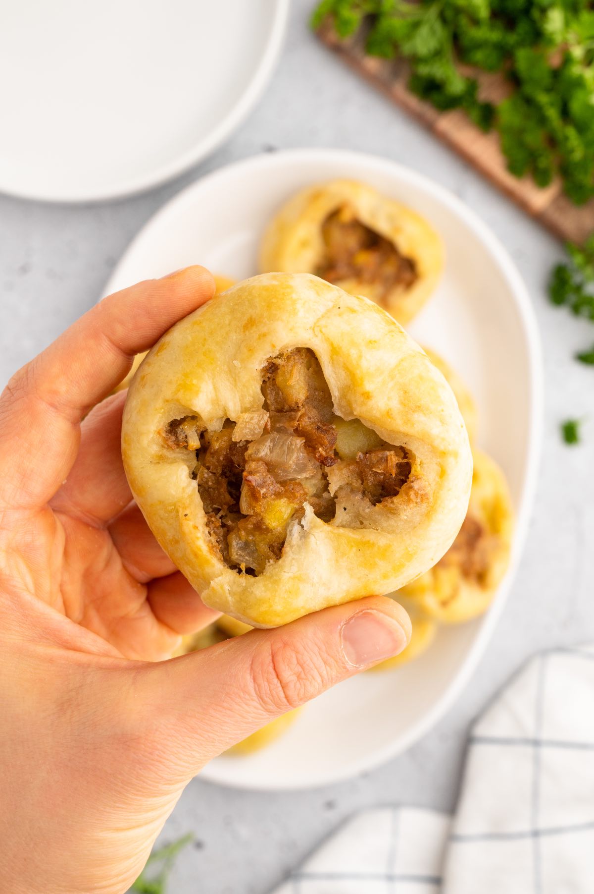 Woman holding up a potato knish. 