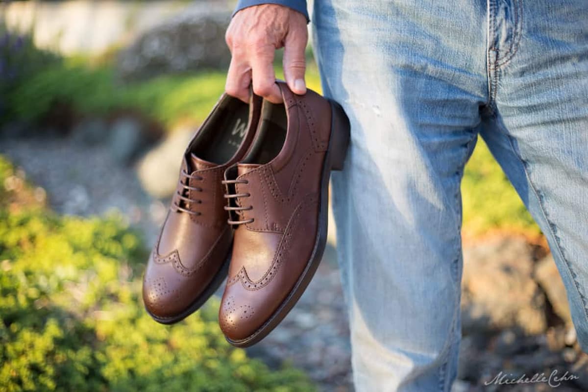 A man holding a pair of vegan shoes from Will's Vegan Shoes.