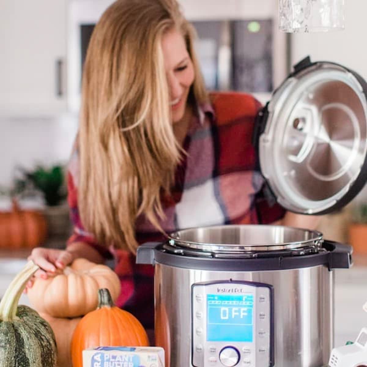 A woman standing behind an instant pot/pressure cooker combo. 