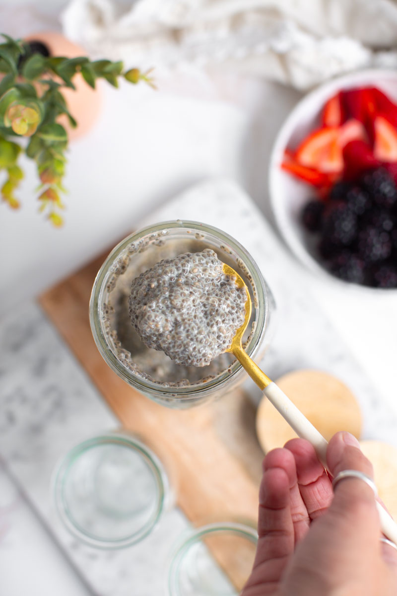 A hand mixing the chia seed pudding with a spoon.