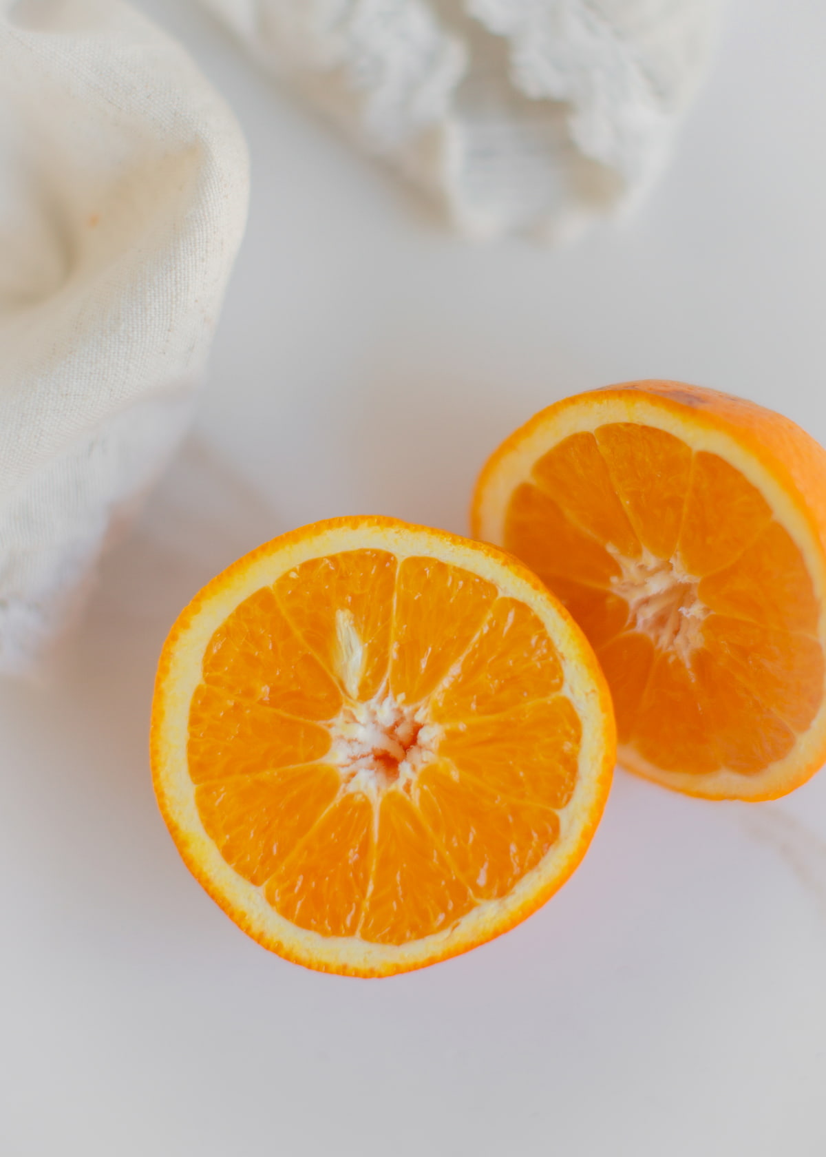 An orange sliced in half on a cutting board.