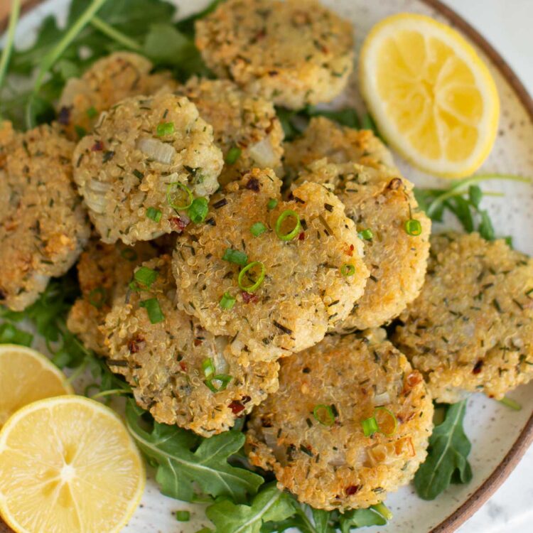 Vegan quinoa nuggets stacked on a plate of greens.