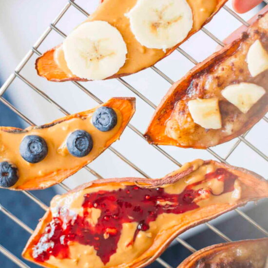 Slices of sweet potato toast on a cooling rack, topped with nut butters, berries, and jam.