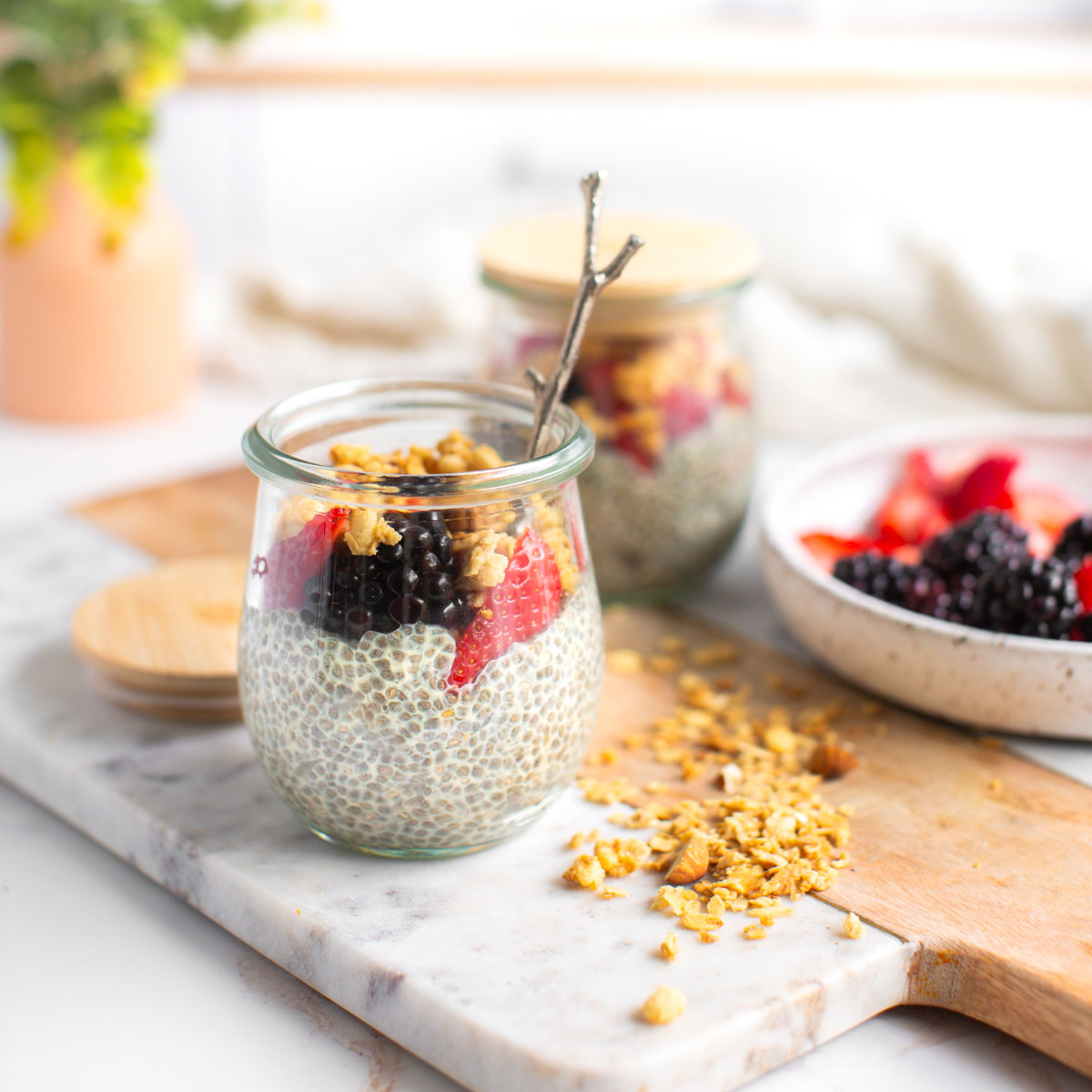 Vanilla chia seed pudding in small glass jars topped with fresh berries and chopped nuts.