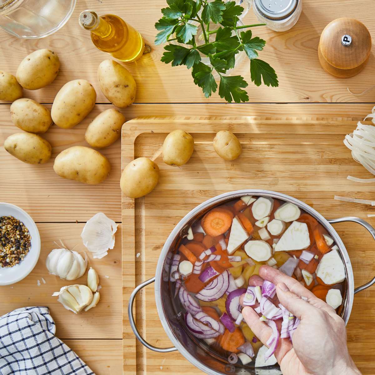 A cutting board with vegan bouillon and soup ingredients and a soup stock pot.