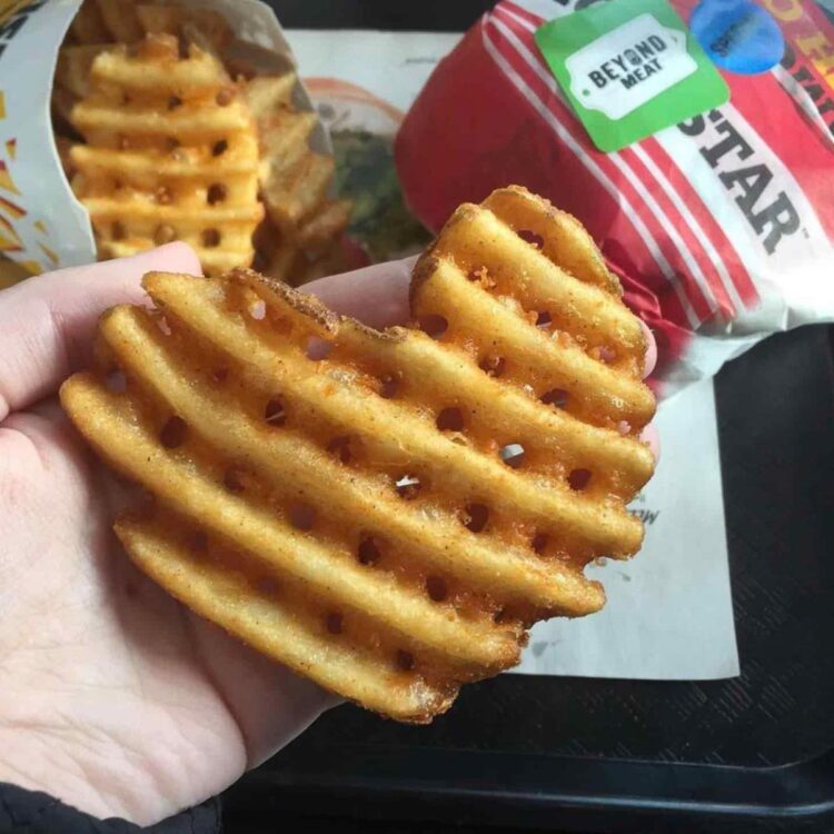 A hand holding a vegan waffle fry at Carl's Jr.