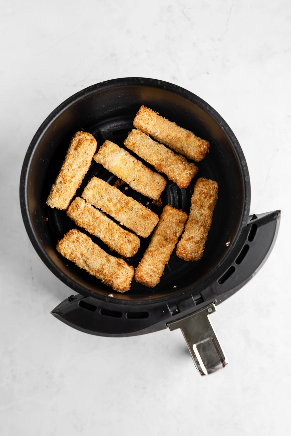 Golden tofu wings in an air fryer basket.