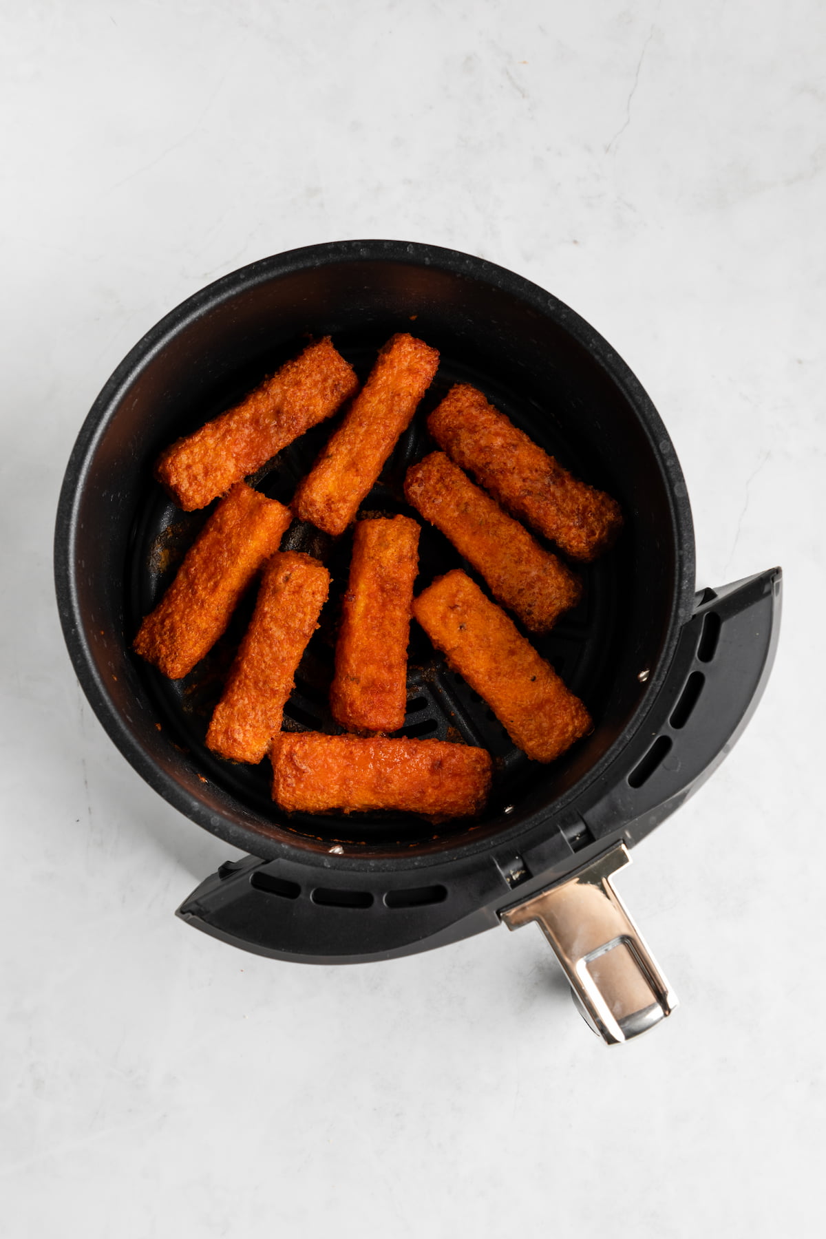 Crispy buffalo tofu wings in an air fryer basket.