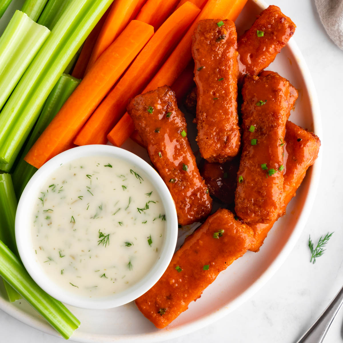 Buffalo tofu wings on a plate with vegan ranch.