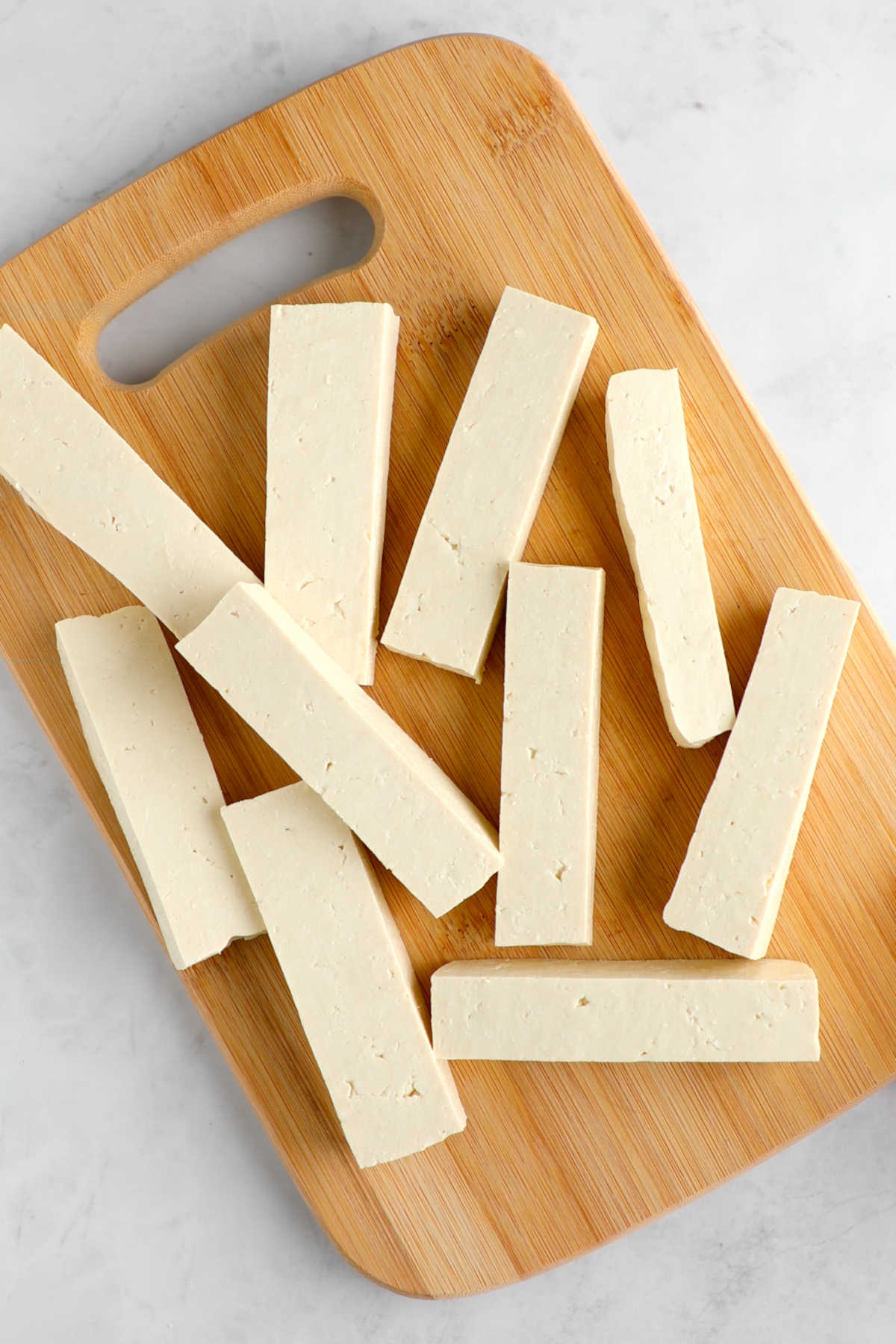 Tofu cut into thick slices on a cutting board.