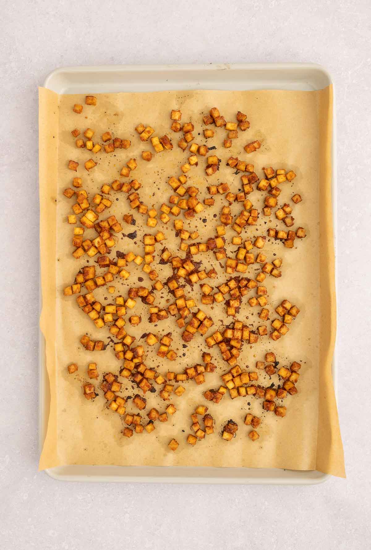 Baked tofu bacon cubes on a parchment-lined tray, ready to top vegan carbonara pasta.