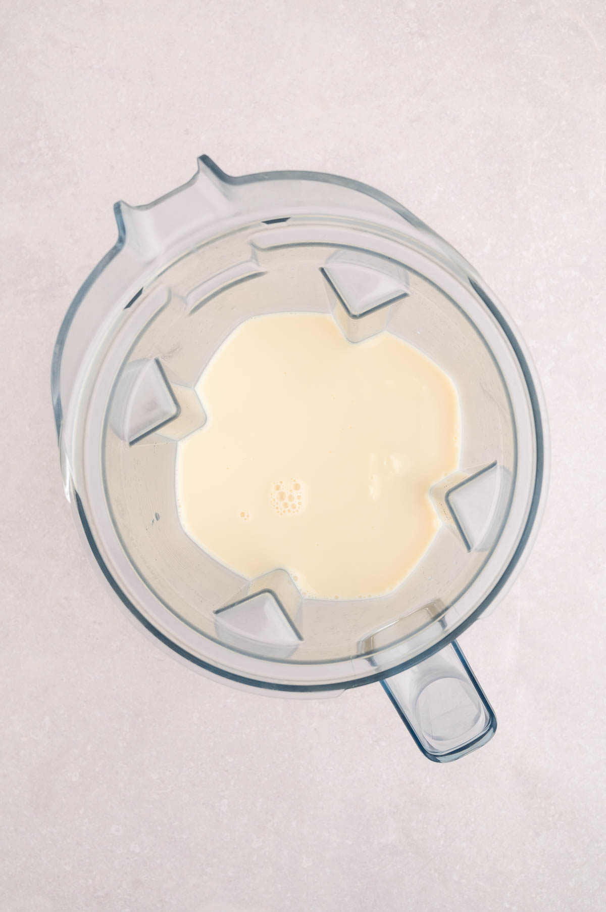Blended tofu and soy milk base in a high-speed blender, ready to make creamy vegan carbonara sauce.