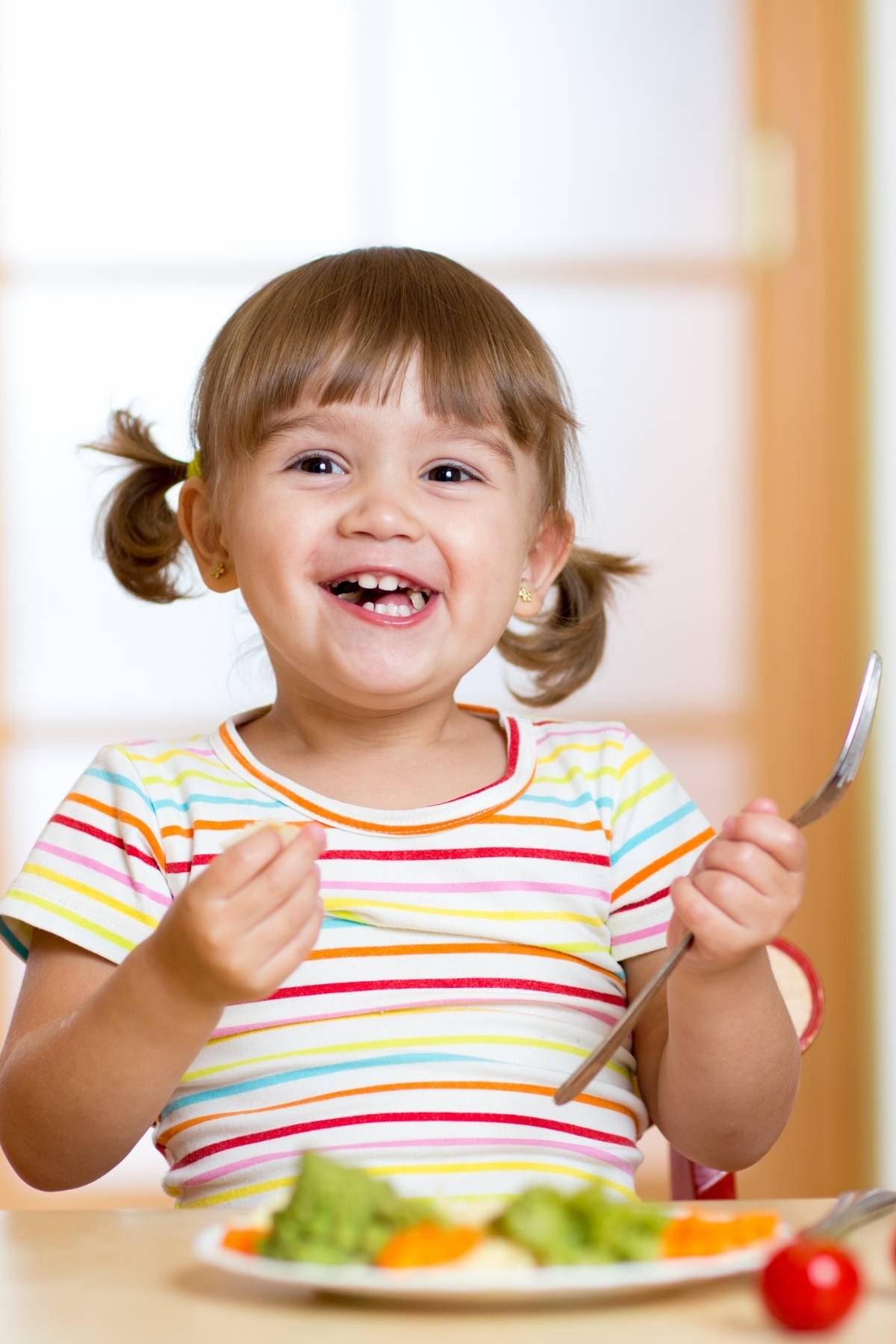 A happy, smiling child eating healthy vegan snacks.