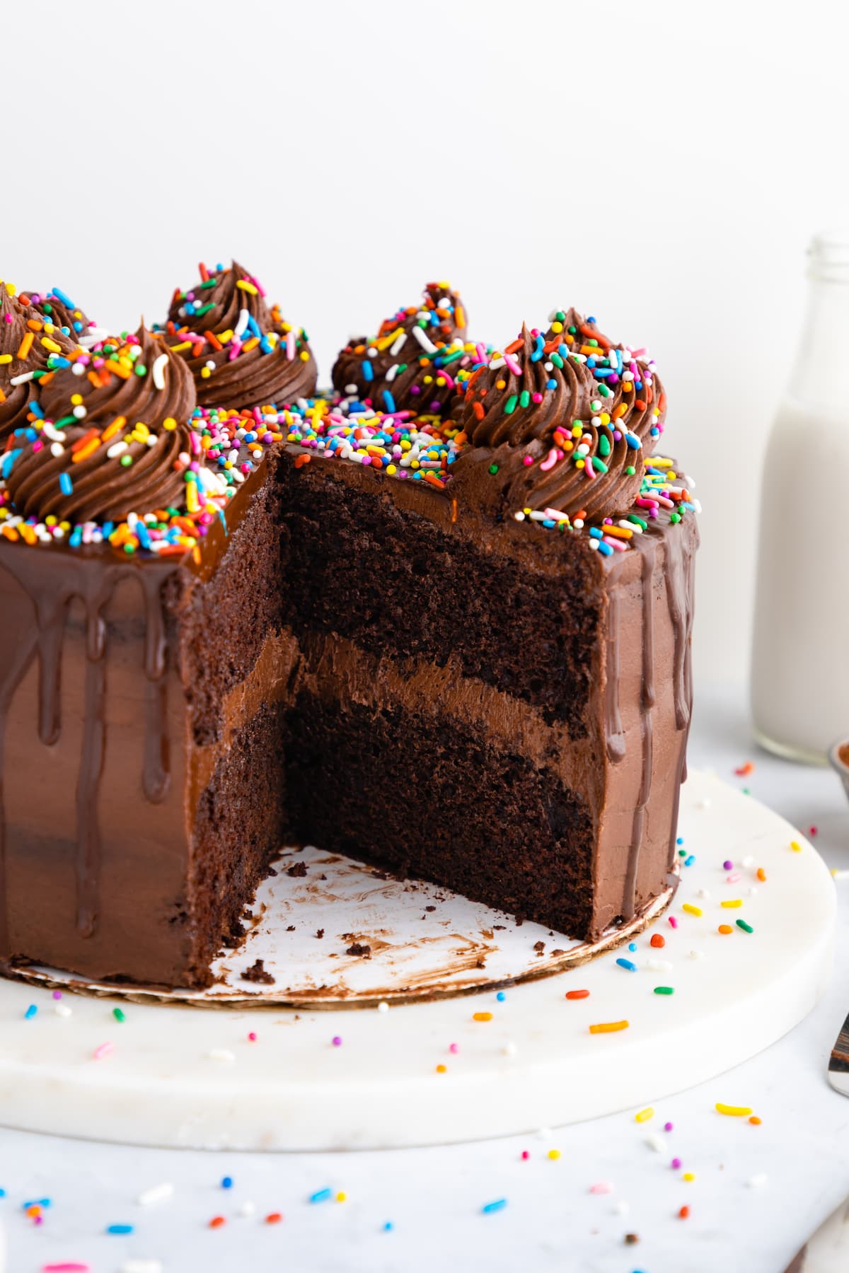 Vegan chocolate cake with a slice missing, displaying the two layers inside.