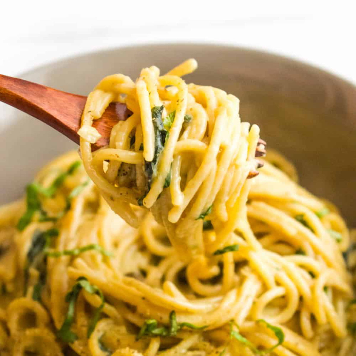 A wooden spoon lifts up a scoop of vegan one-pot pasta noodles.