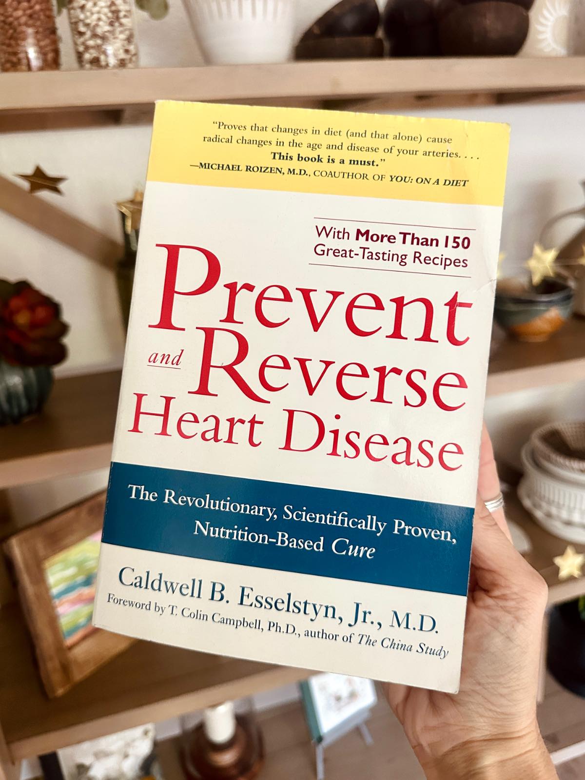 Photo holding out the book Prevent and Reverse Heart Disease by Dr. Caldwell Esselstyn showing the cover.