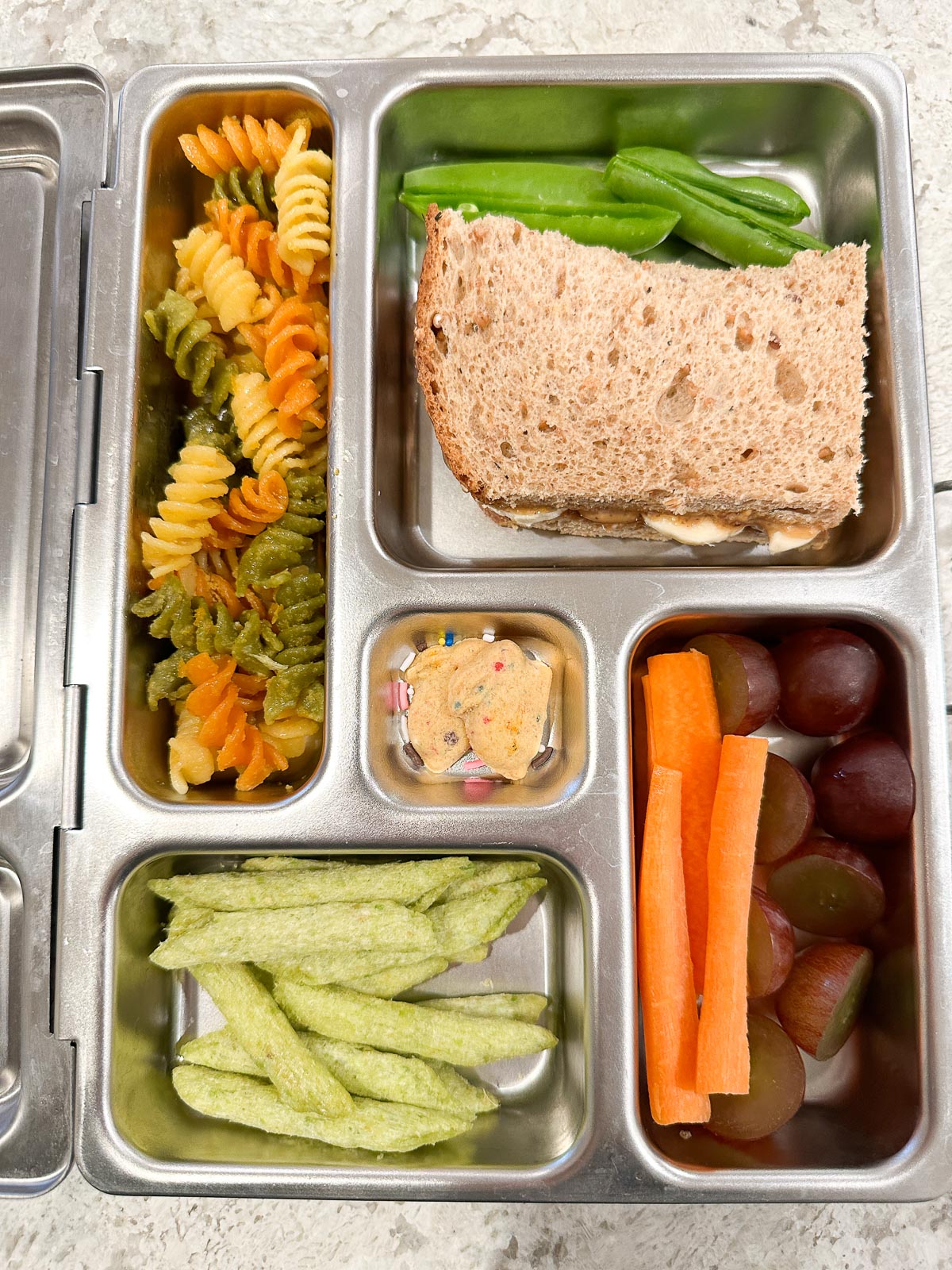 Stainless steel bento lunchbox filled with colorful plant-based vegan lunch items for kids.