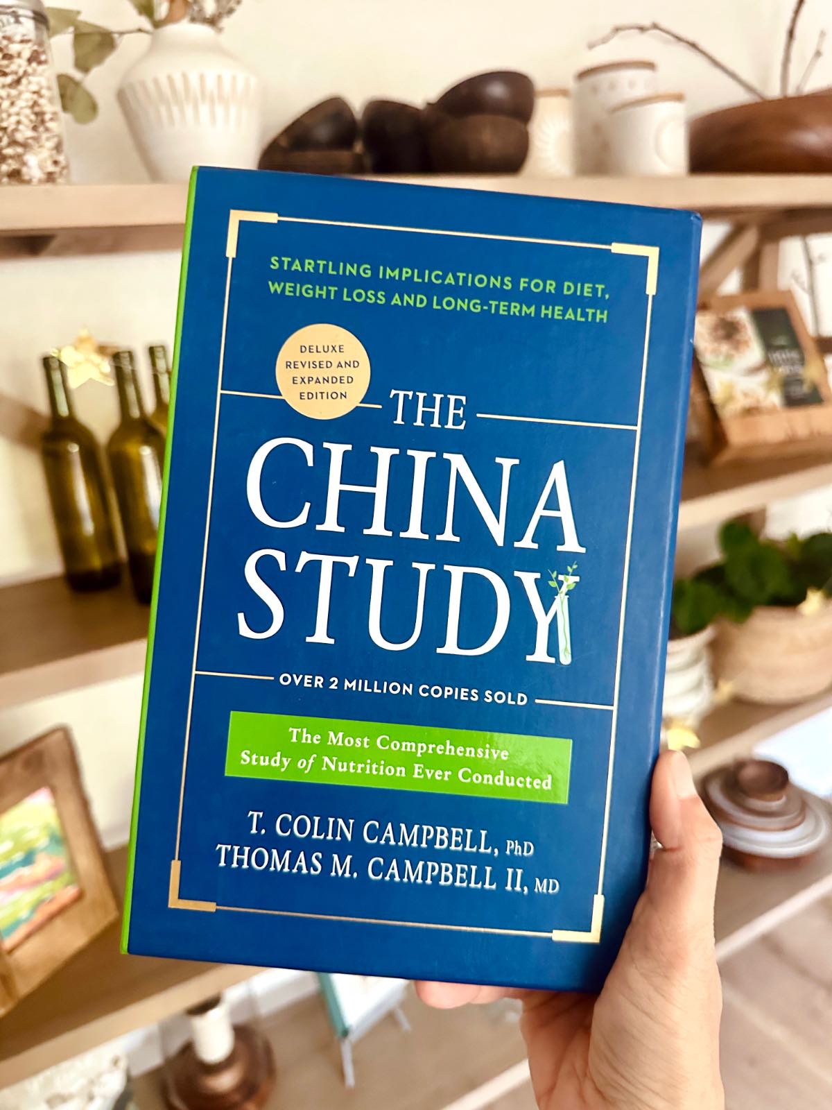 Woman holding out a copy of the book The China Study by Dr. Colin Campbell showing the cover.