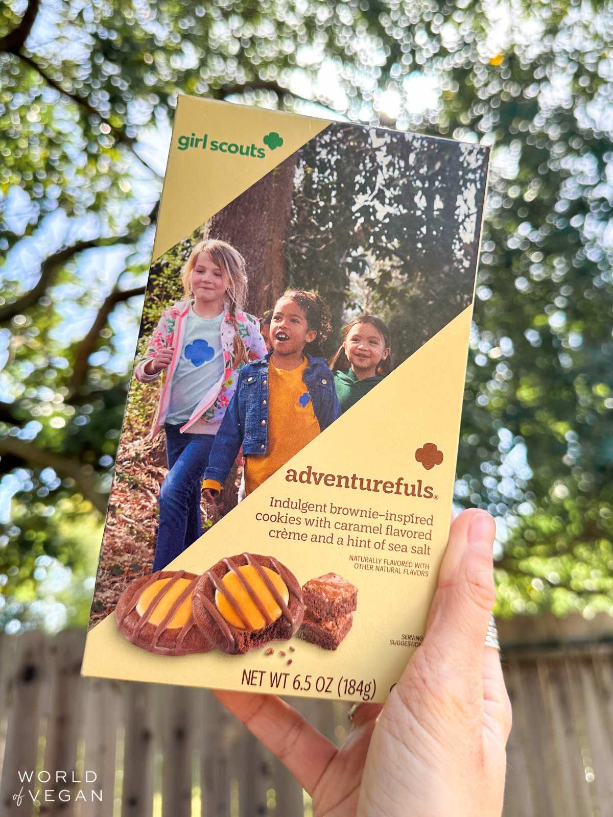 Vegan woman holding up a box of Adventurefuls Girl Scouts cookies outside. 