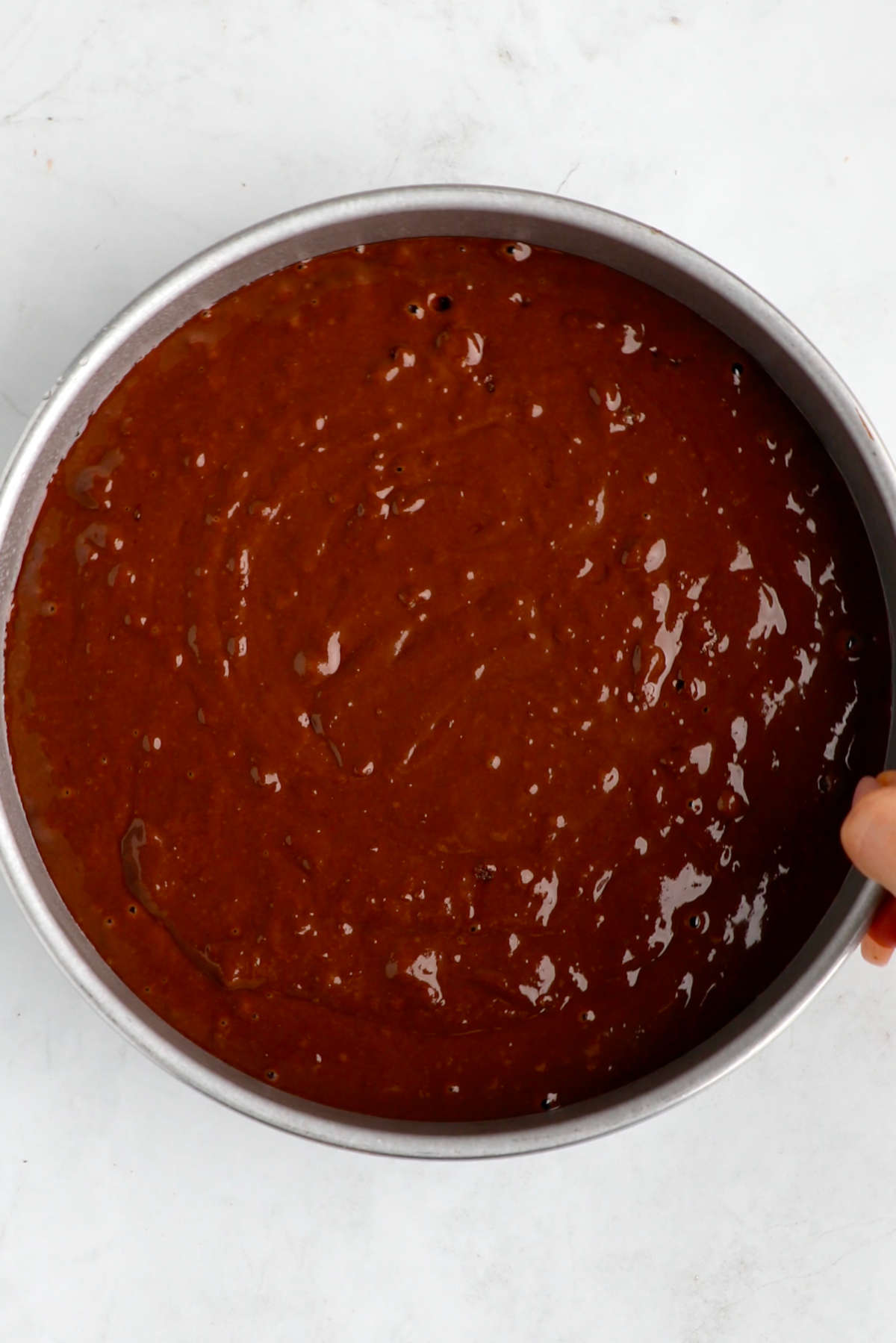 The vegan chocolate cake batter added to a cake pan.