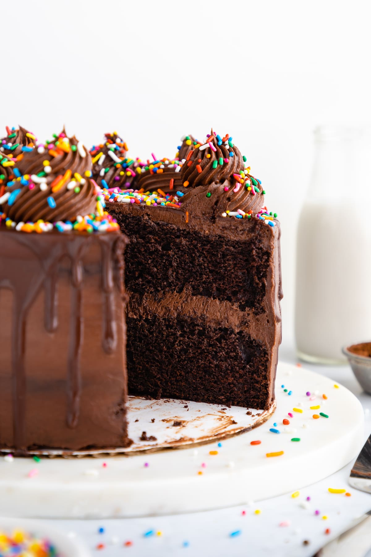 Vegan chocolate cake with a slice missing, displaying the two layers inside.