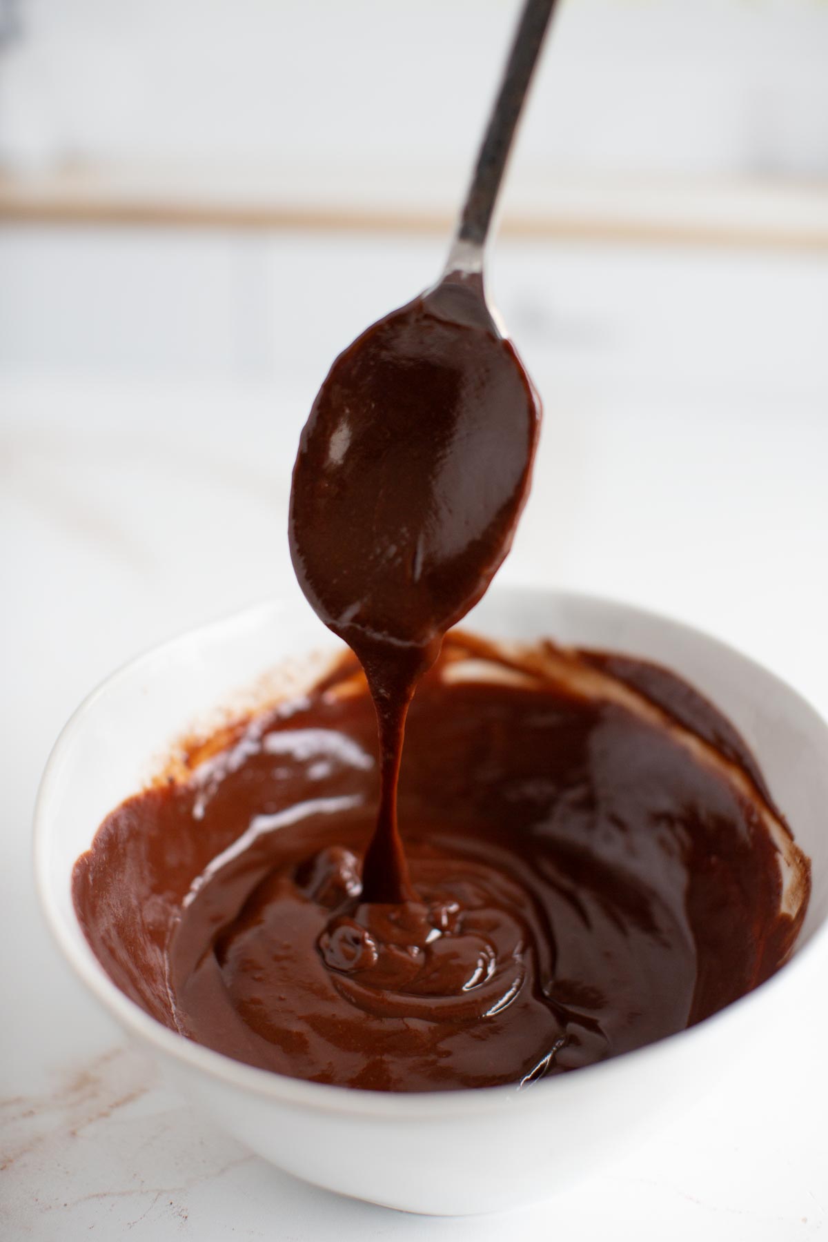 Vegan ganache dripping off a spoon into a bowl.