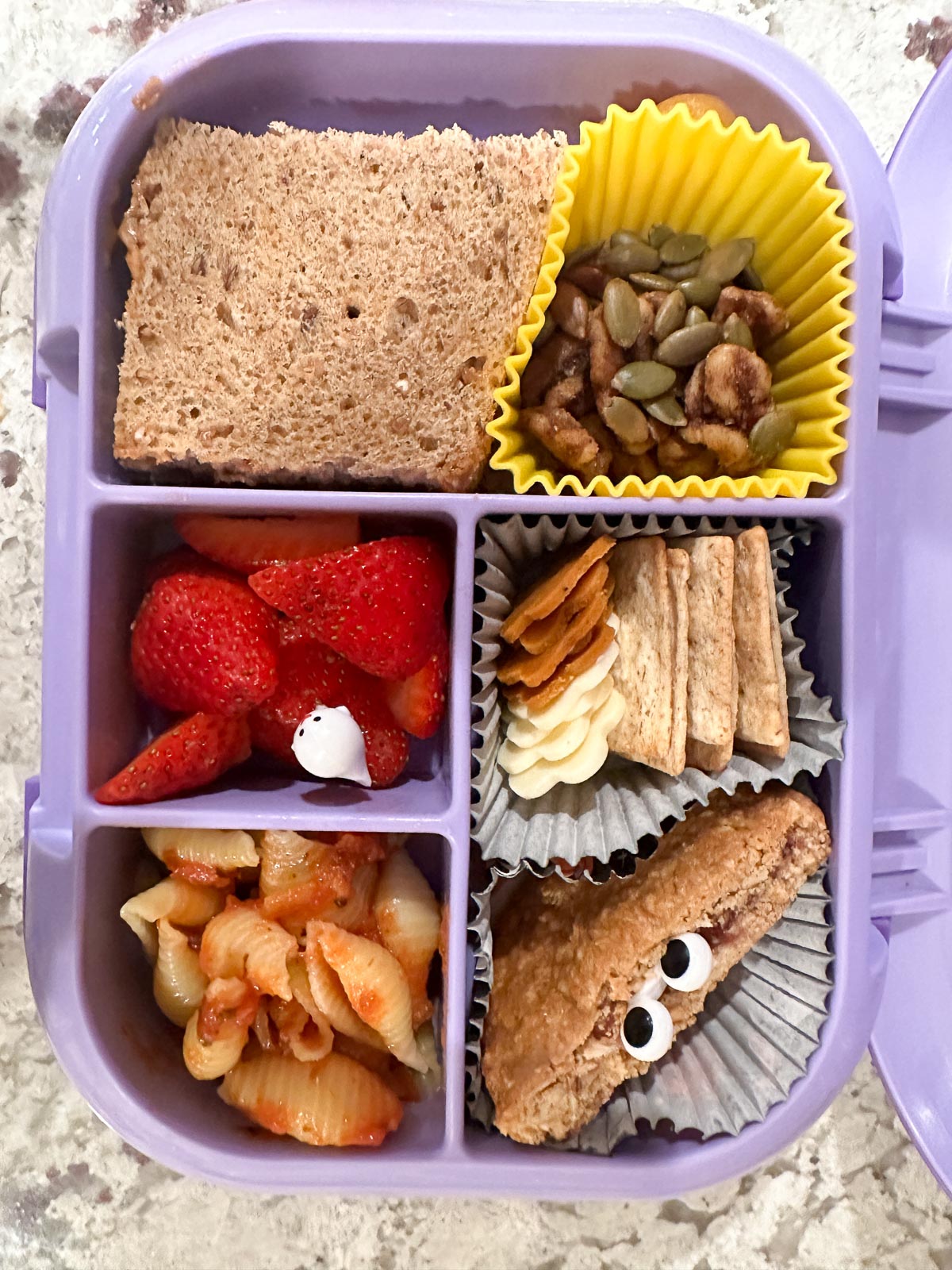 Open bento lunchbox with a variety of kid-friendly vegan lunch foods.