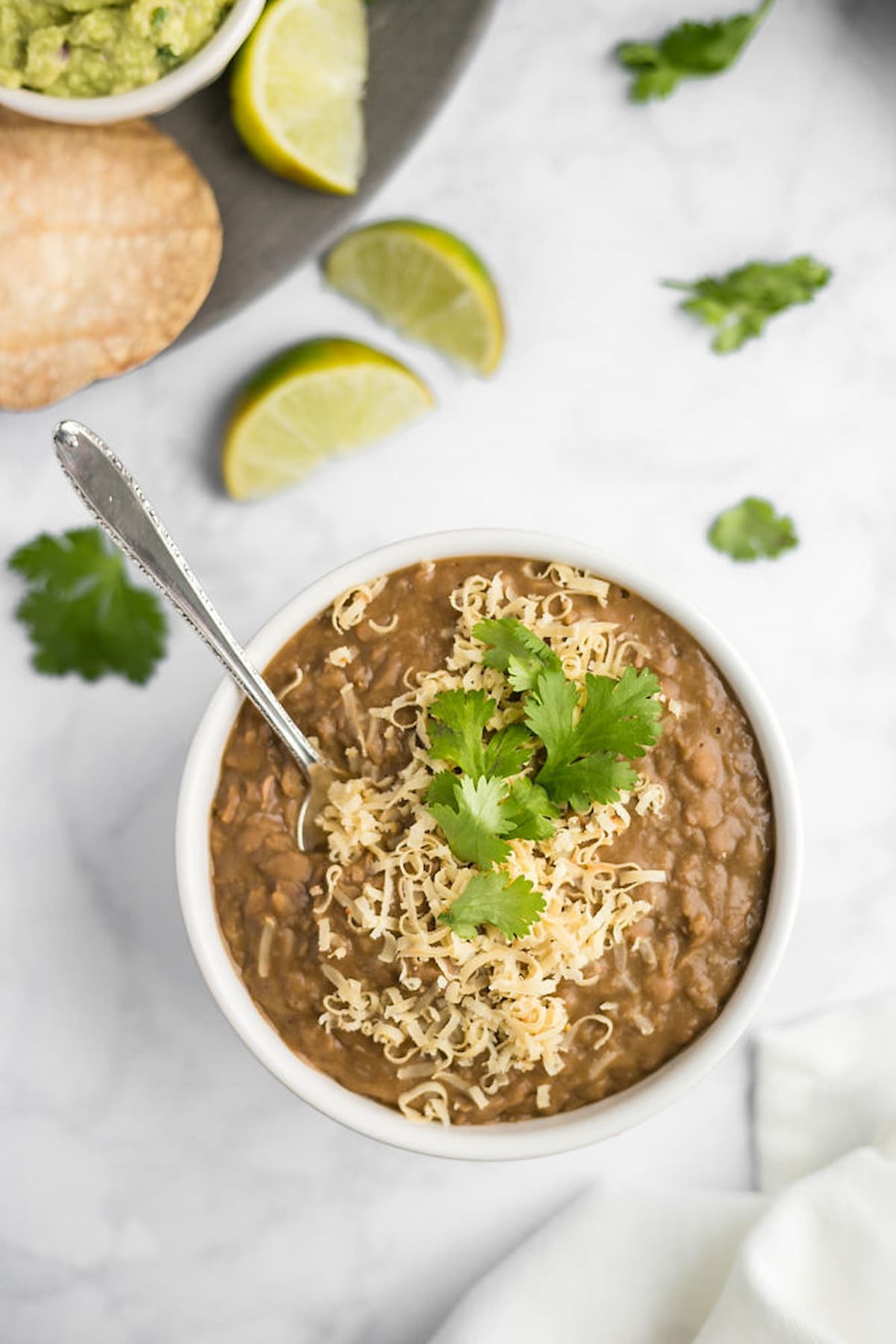 Vegan instant pot refried beans topped with vegan cheese and cilantro leaves.