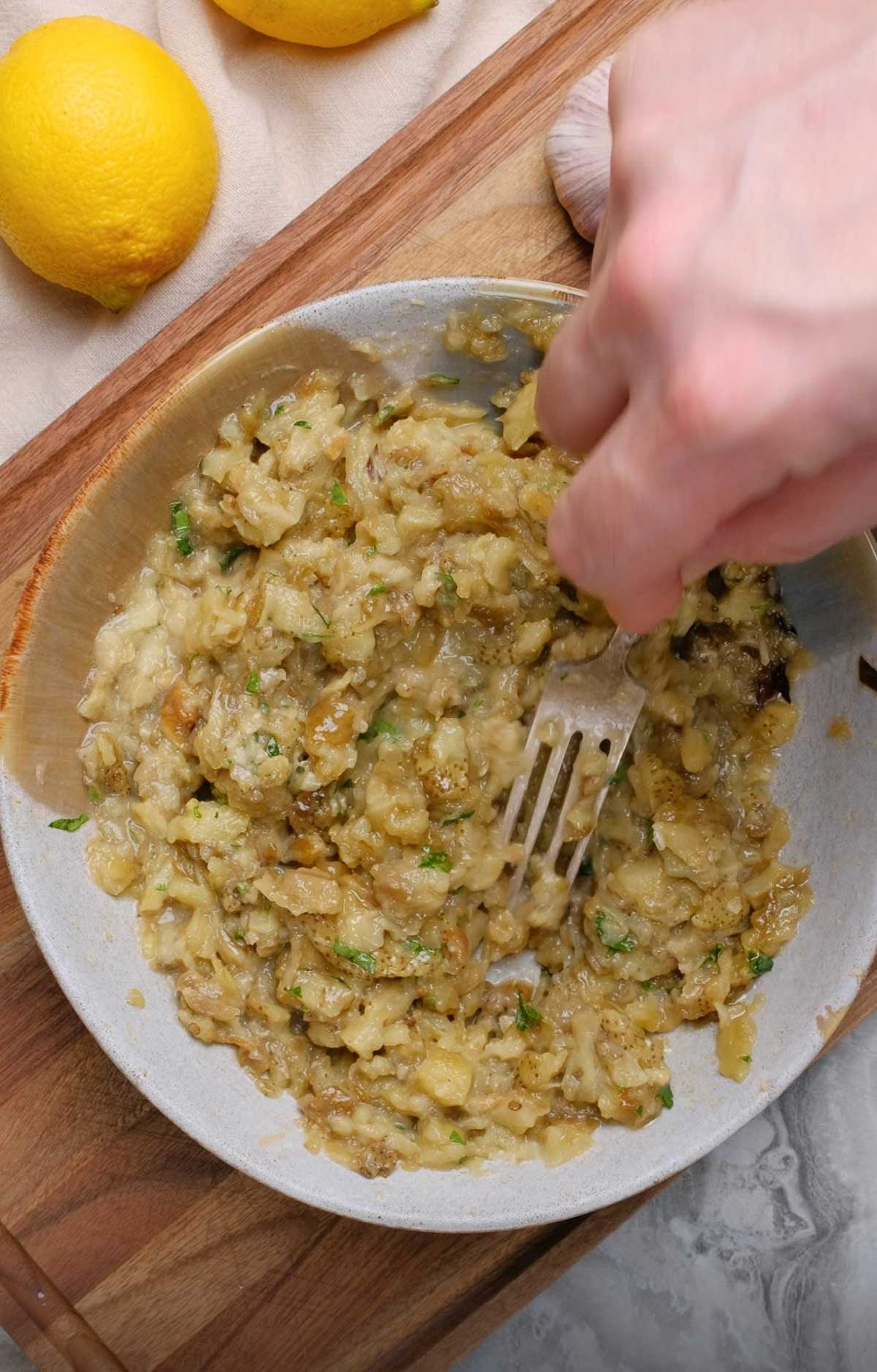 Eggplant being mashed with a fork.