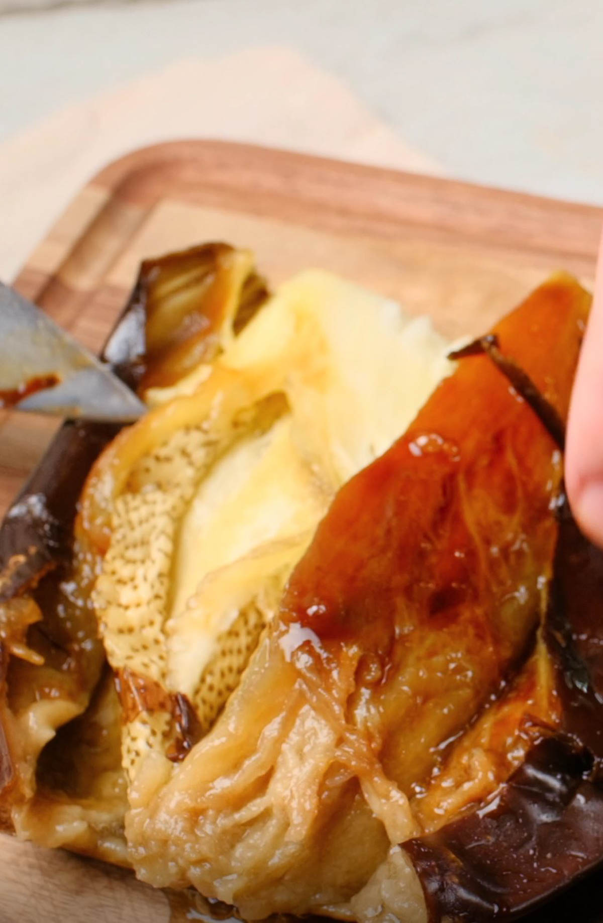 A roasted eggplant being sliced open.