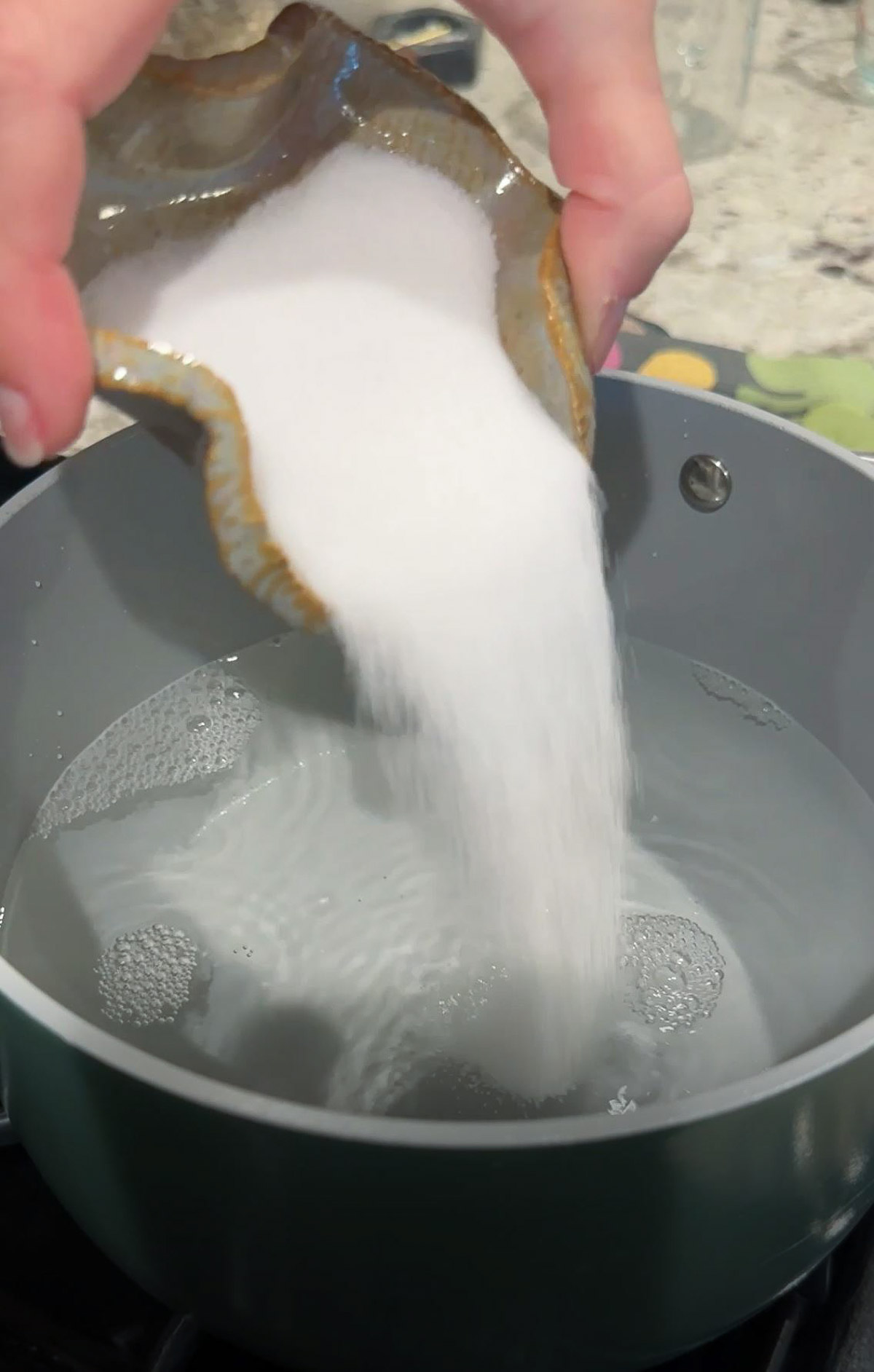 Salt being added to boiling water in a pot.