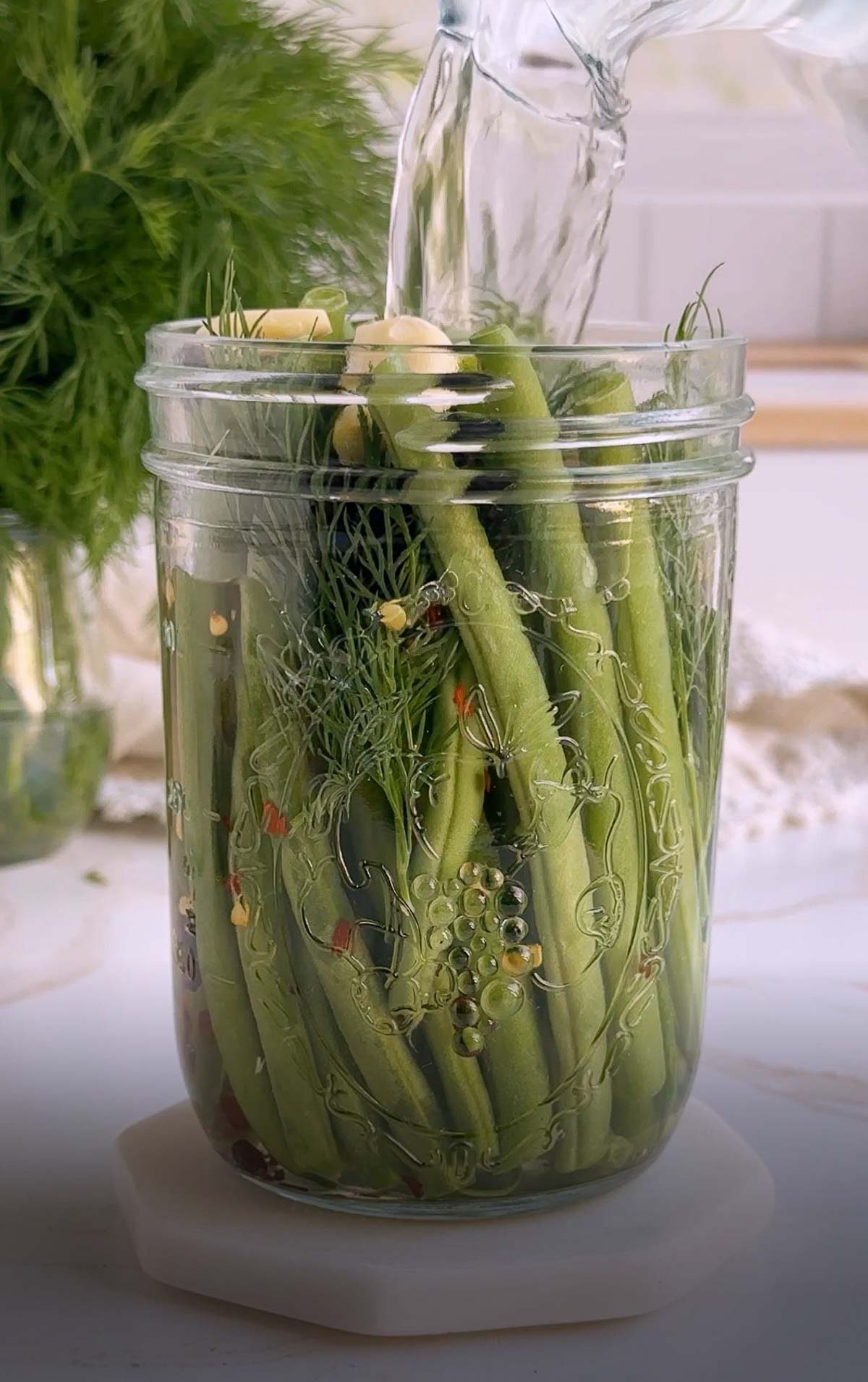 Pickled brine being poured over green beans.