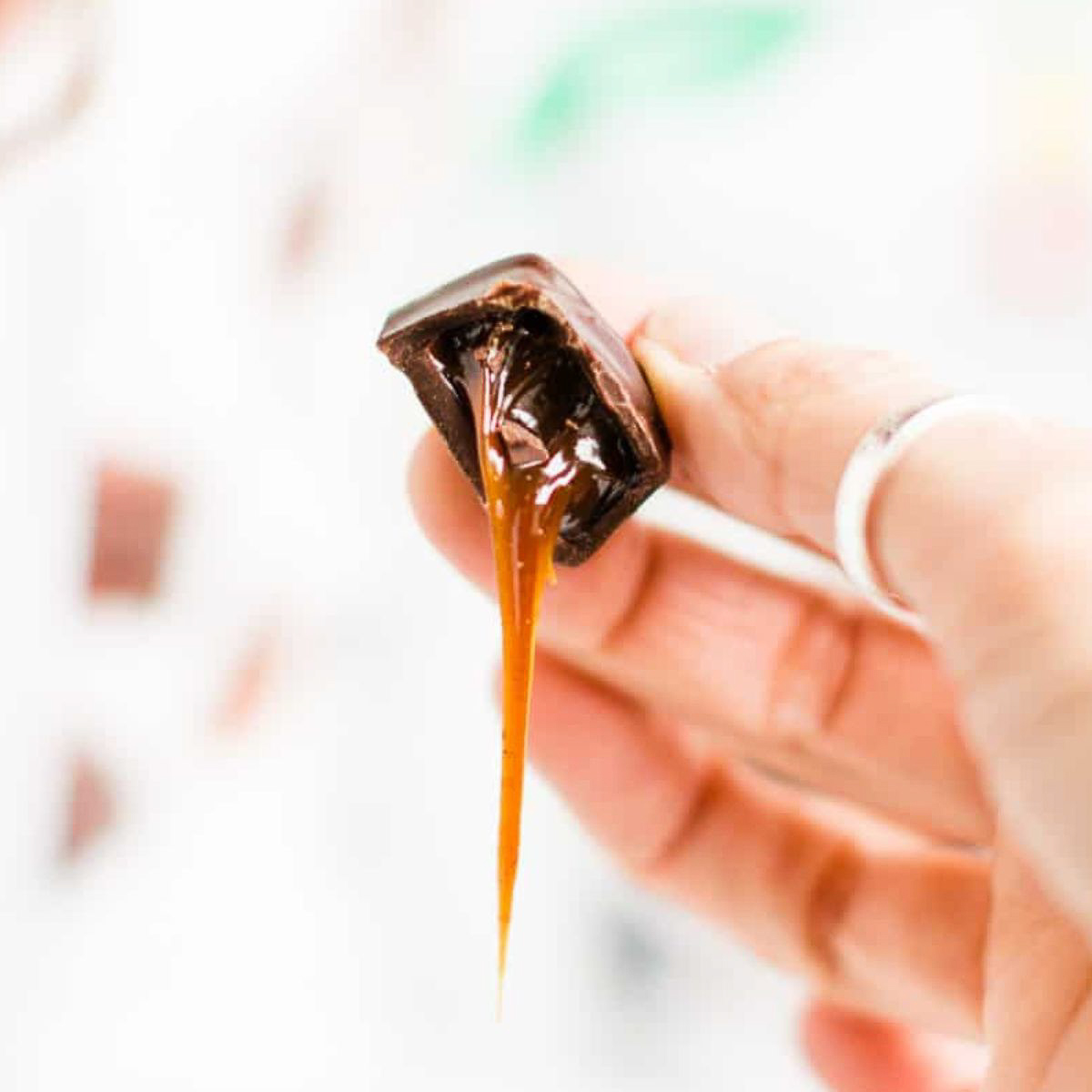 A hand holding a vegan chocolate caramel.