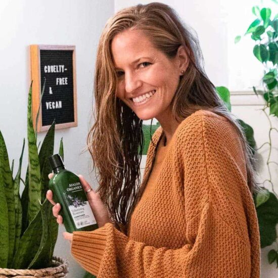 A woman holding a bottle of vegan shampoo.