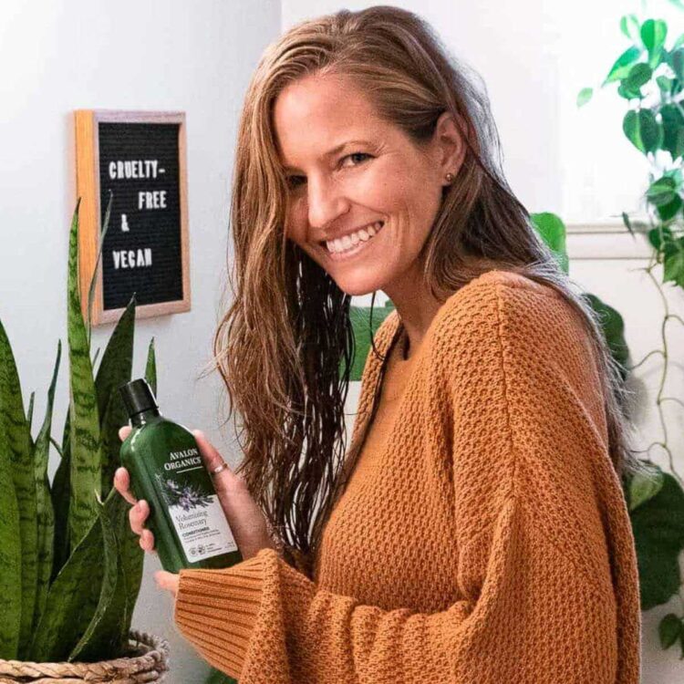 A woman holding a bottle of vegan shampoo.