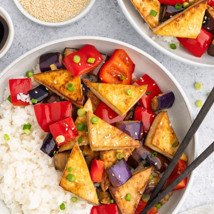 Eggplant tofu in a bowl served with rice and chopsticks.