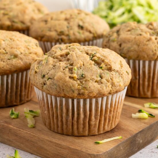 Vegan zucchini muffins on a wooden cutting board.