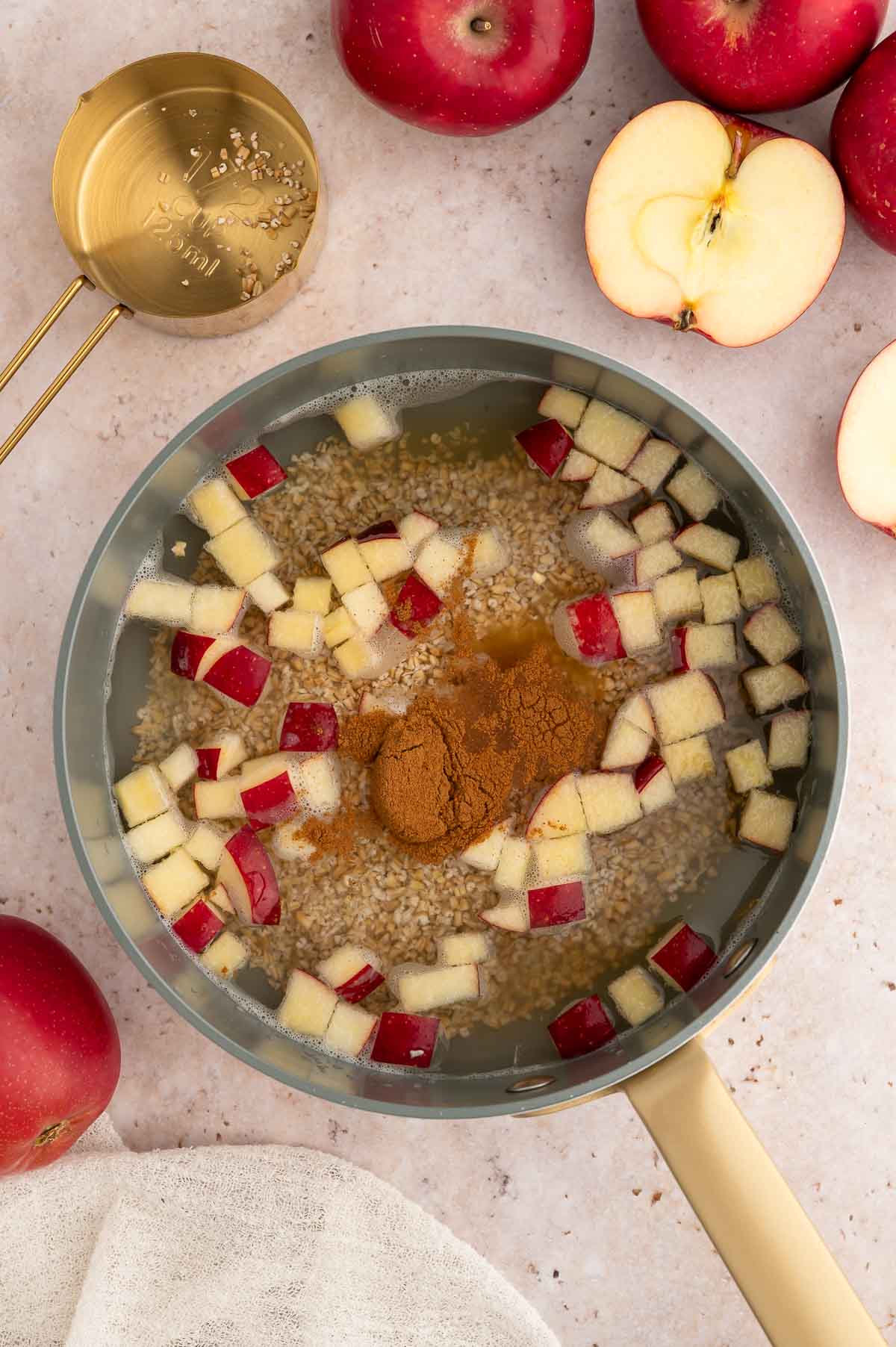 A saucepan with apples, cinnamon, and oats.