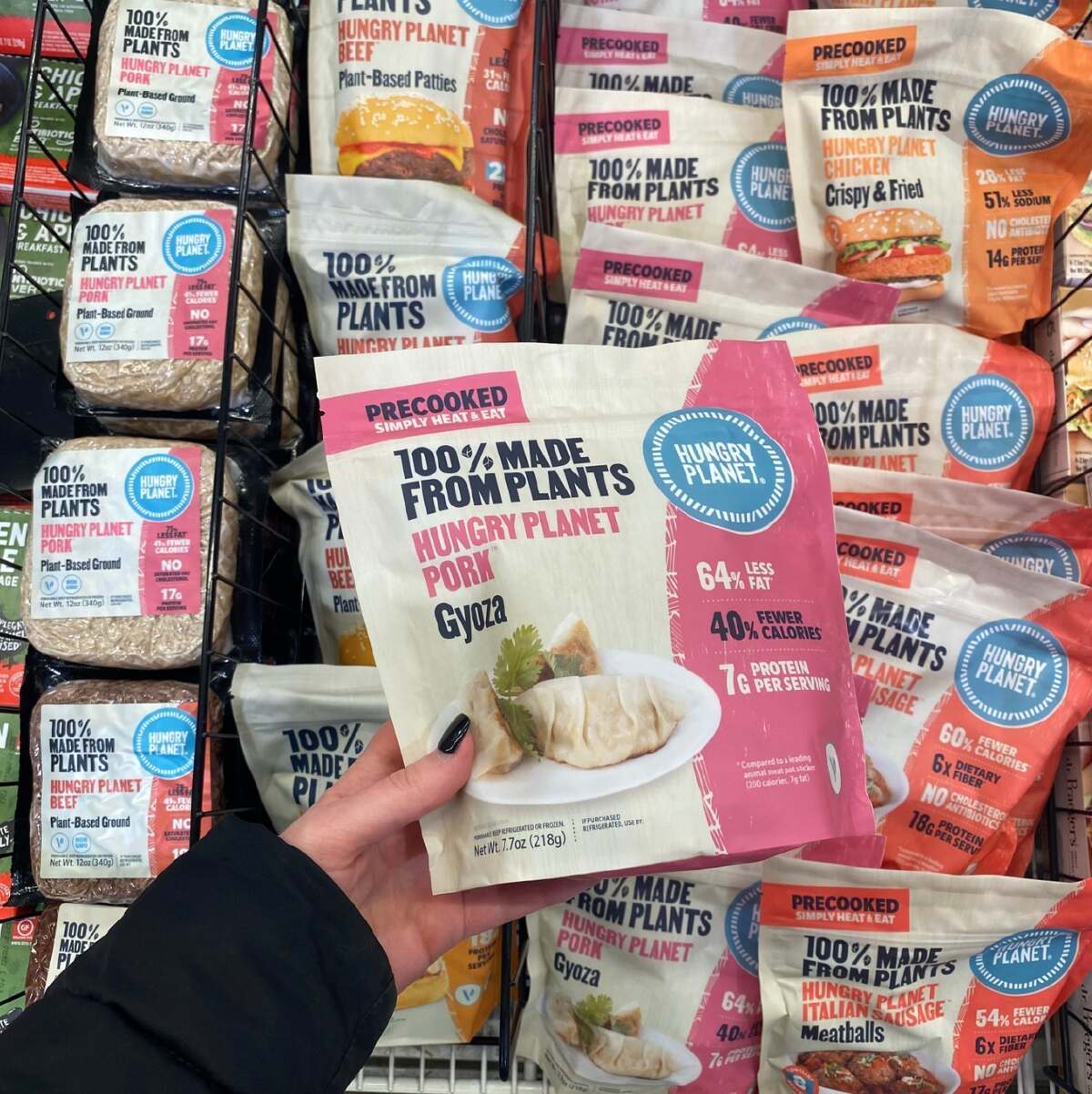 An assortment of Hungry Planet vegan options with a hand holding a package of plant-based gyoza.
