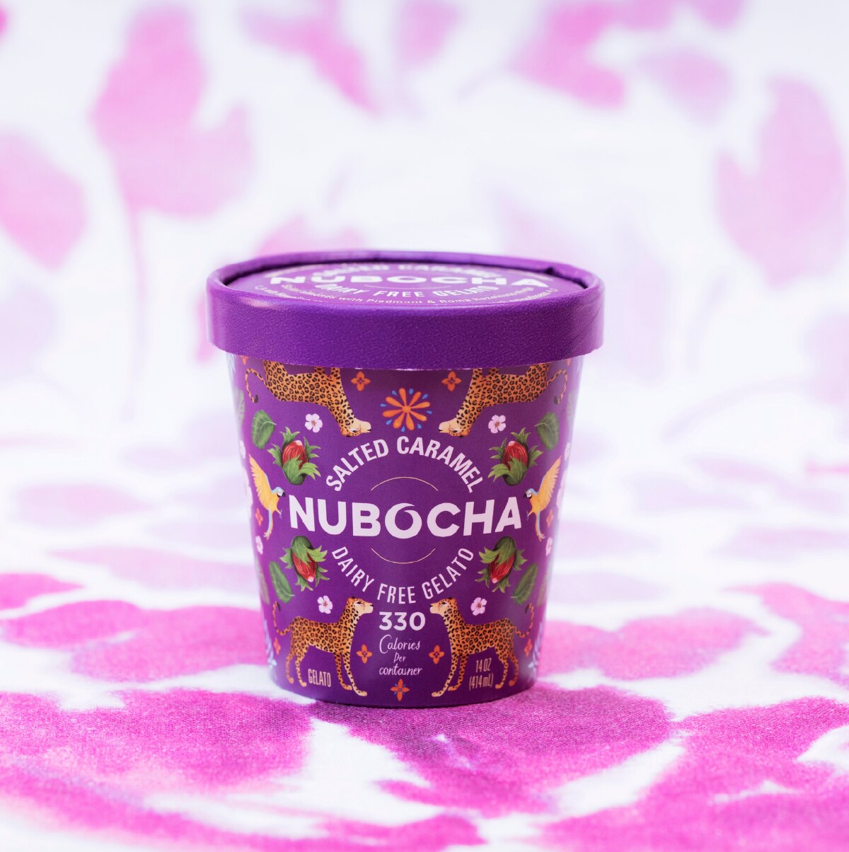 A purple container of Nubocha dairy free gelato in Salted Caramel flavor against a purple and white patterned background. 