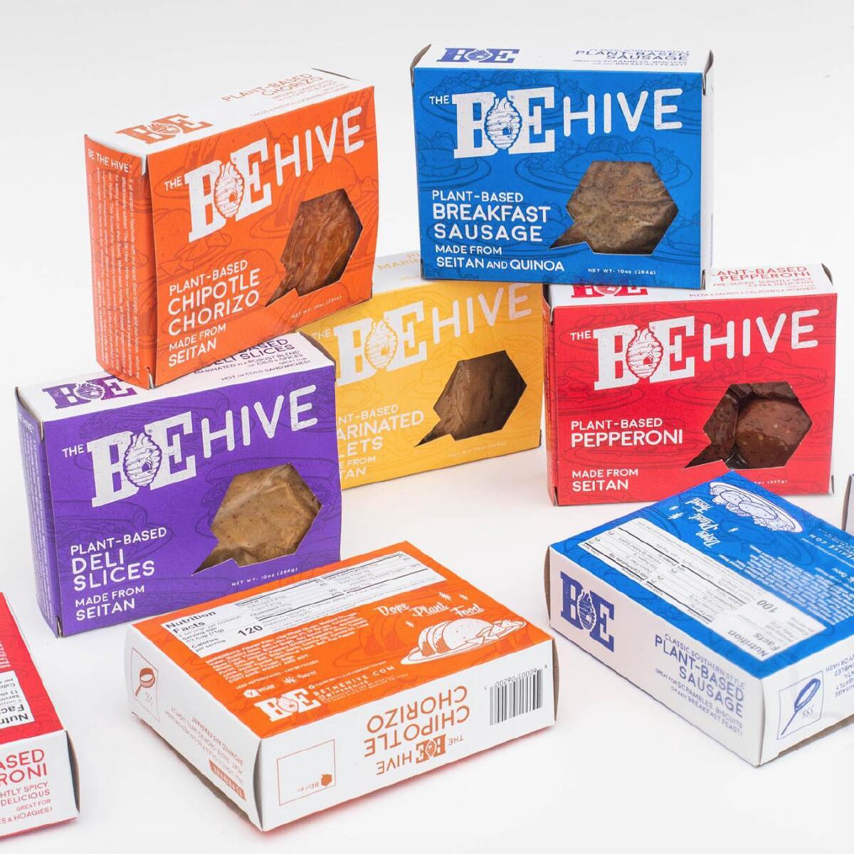 Eight colorful boxes of The Be-Hive plant-based meat products stacked together against a white background.