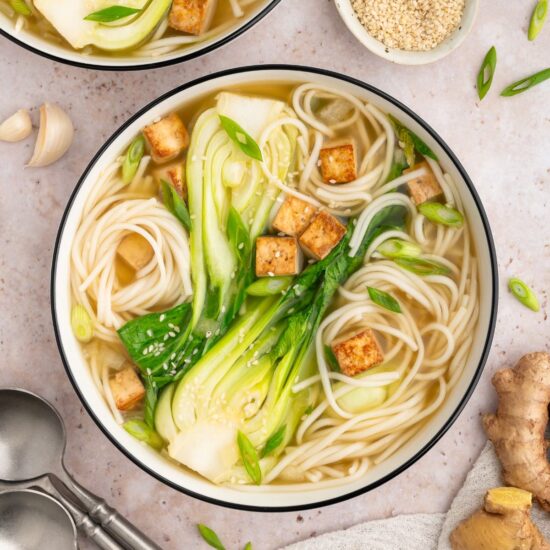 Bok choy soup in a bowl with noodles and tofu cubes.