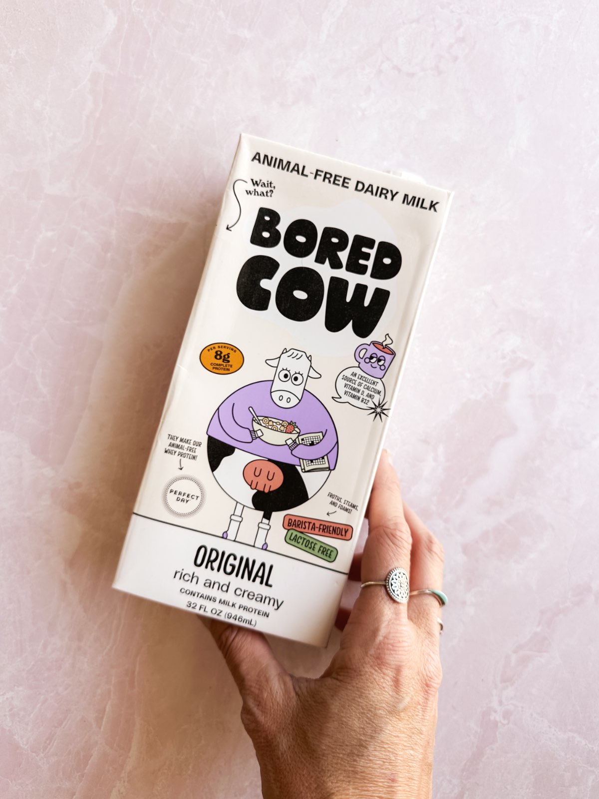 A carton of animal-free milk from Bored Cow on a pink surface. 