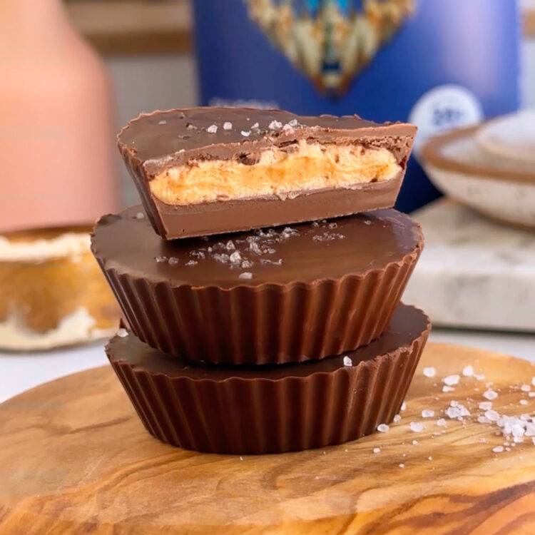 Three vegan peanut butter cups stacked on each other with the top one sliced in half revealing the inside.