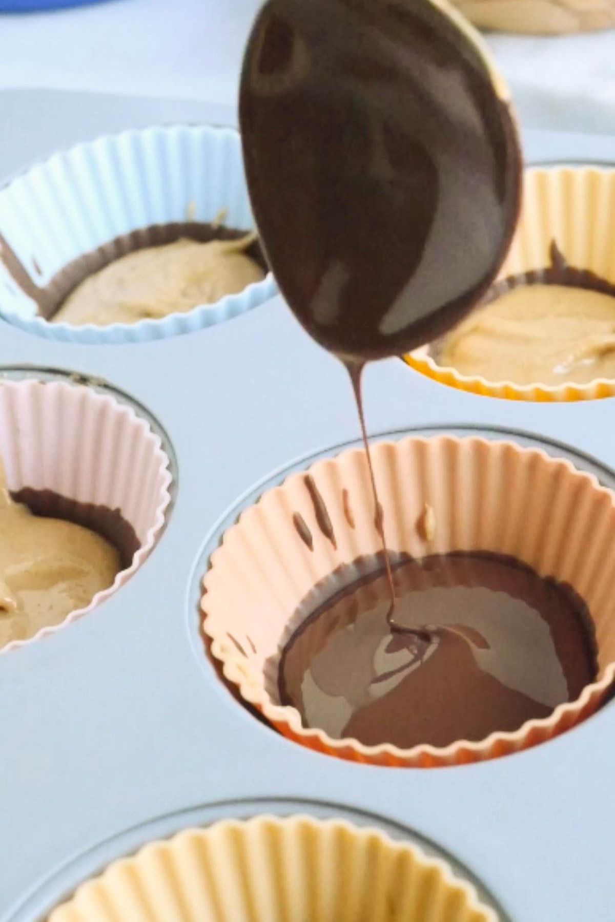 Vegan melted chocolate being spooned into a silicone muffin tin.