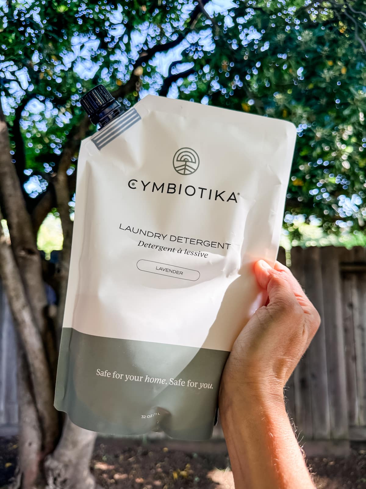 A hand holding up a package of Cymbiotika's vegan laundry detergent.