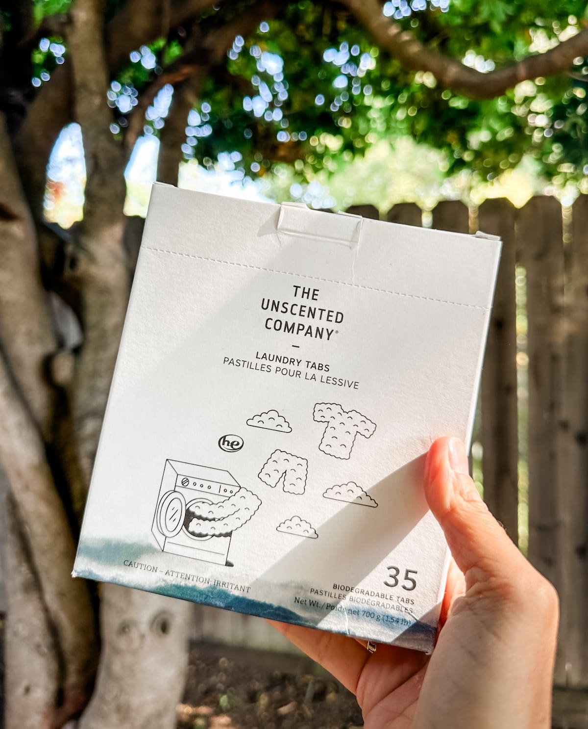 A hand holding up a package of The Unscented Company's vegan laundry tabs.
