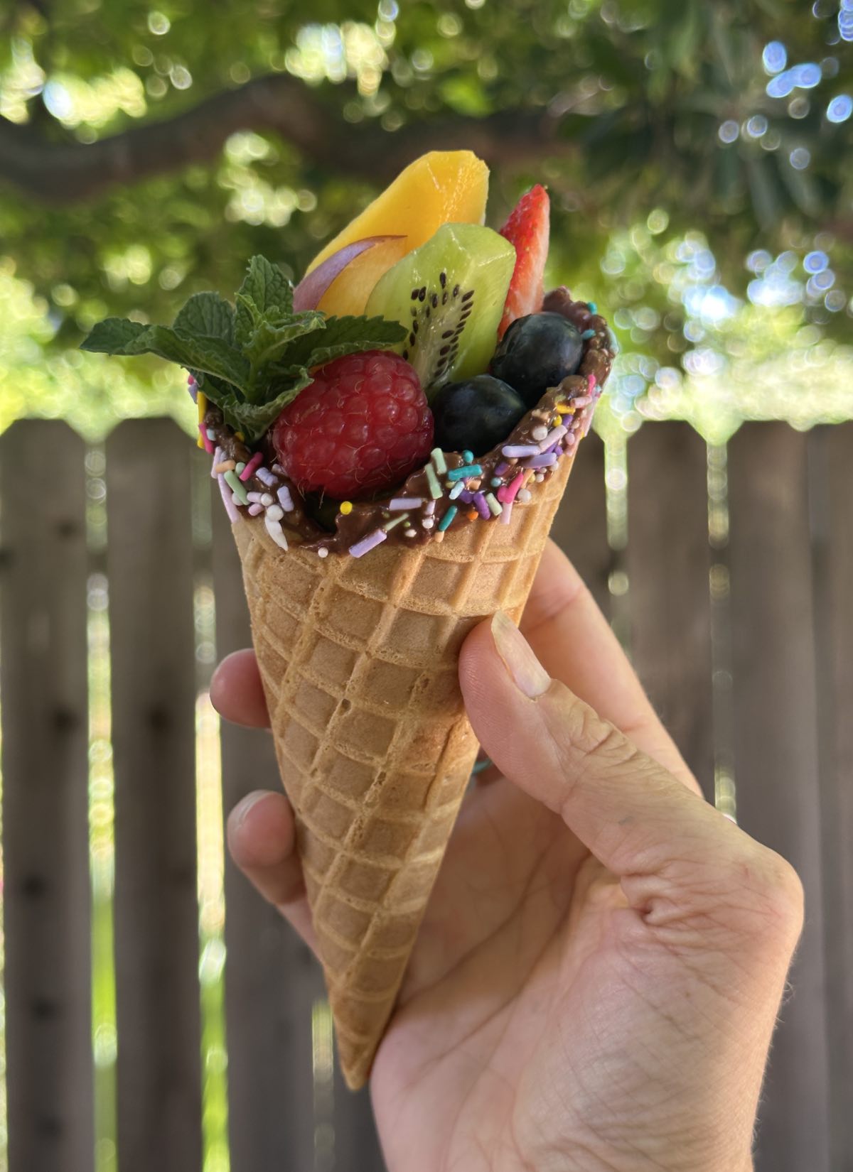 A chocolate fruit cone with sprinkles.