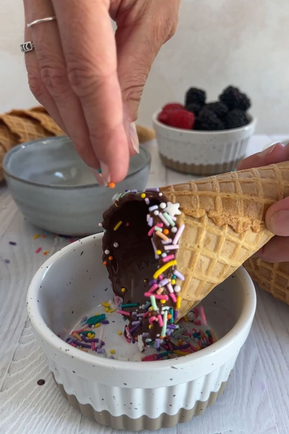 Sprinkles being added to an ice cream cone.